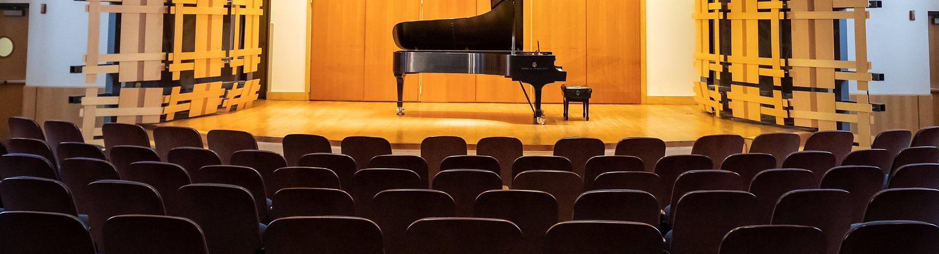 无人看管的钢琴在空礼堂的舞台上无人看管的钢琴. 